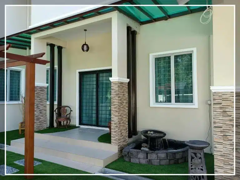 Kenapa Rumah Nampak Serabut Walaupun Dah “Minimalis”? 1 Modern house entrance with small garden and water fountain, featuring stone wall accents and sliding glass doors.