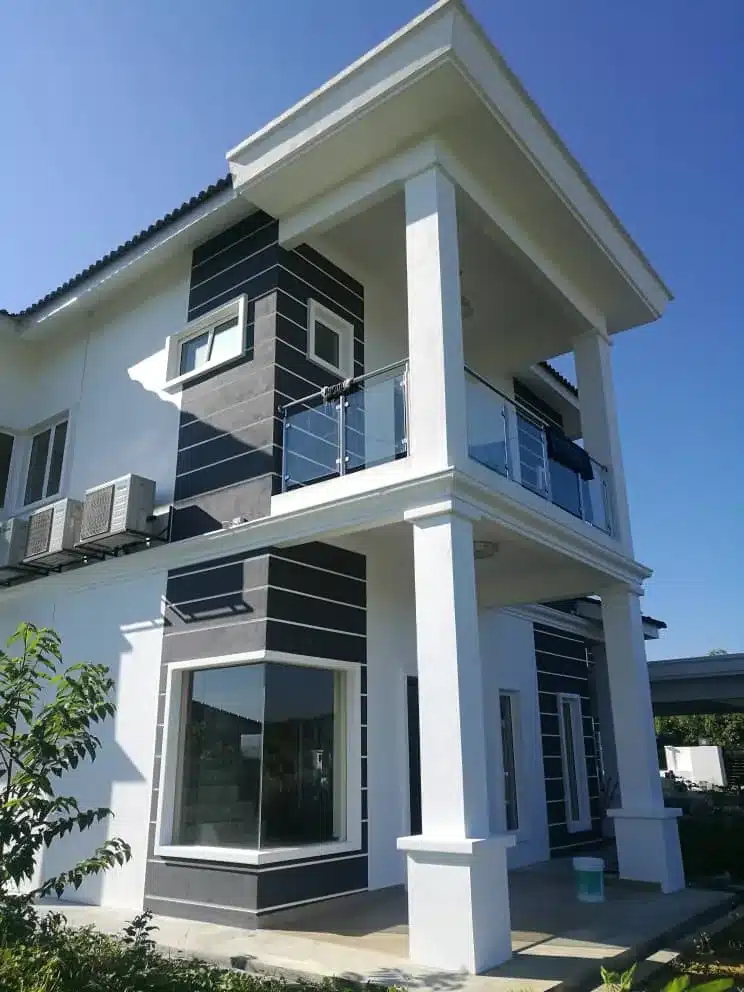 Modern two-story house with large windows and balcony against clear blue sky.