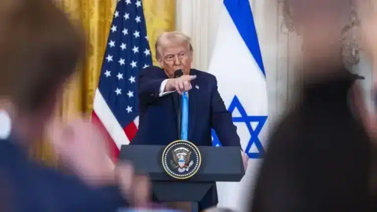 TRUMP: PRESIDEN YANG DICAP SEBAGAI FIRAUN ZAMAN KINI - ANALISIS MENDALAM KEPIMPINAN KONTROVERSI YANG MENGUBAH DUNIA 3 Speaker at podium with U.S. and Israeli flags in background, pointing towards audience during speech.