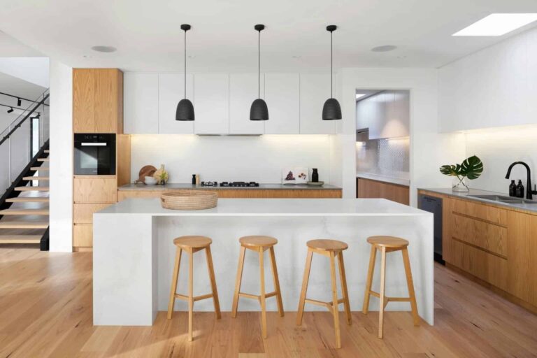 LPPSA Zero Deposit Financing with RumahHQ: A Complete Market Analysis for Malaysian Civil Servants 1 Modern kitchen with wooden floors, white cabinets, island, and four barstools under black pendant lights.