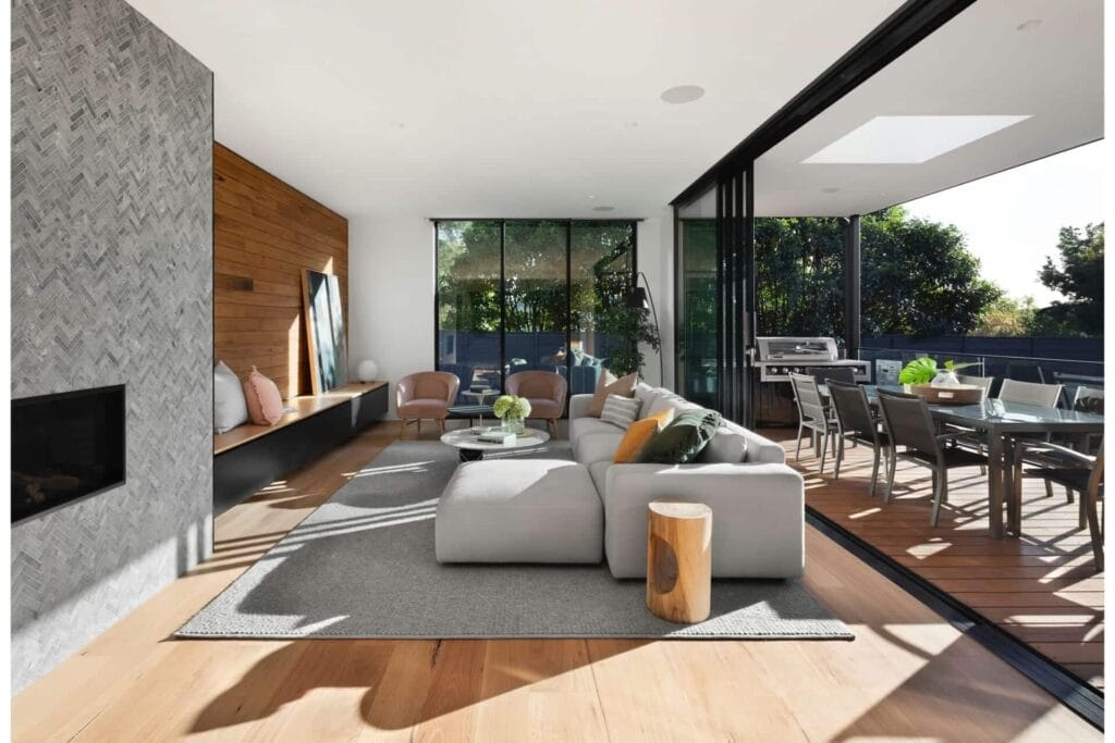 Modern living room with open layout, large windows, cozy decor, and outdoor patio in a contemporary home.