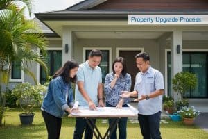 Family reviewing house plans with a contractor outside their home for property upgrade.