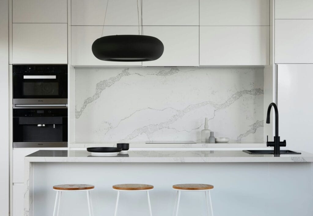 Nak Rumah Cantik Tapi Bajet Ciput? 8 Tips Reka Bentuk Viral RM50K Je Dah Power! 4 Modern kitchen with marble countertop, black faucet, and minimalist decor. Stylish pendant light and white cabinetry.
