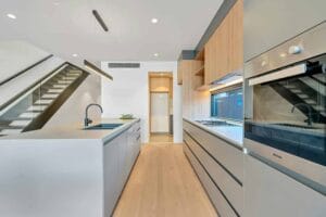Modern kitchen with sleek design, featuring an island, built-in ovens, and minimalist cabinetry.