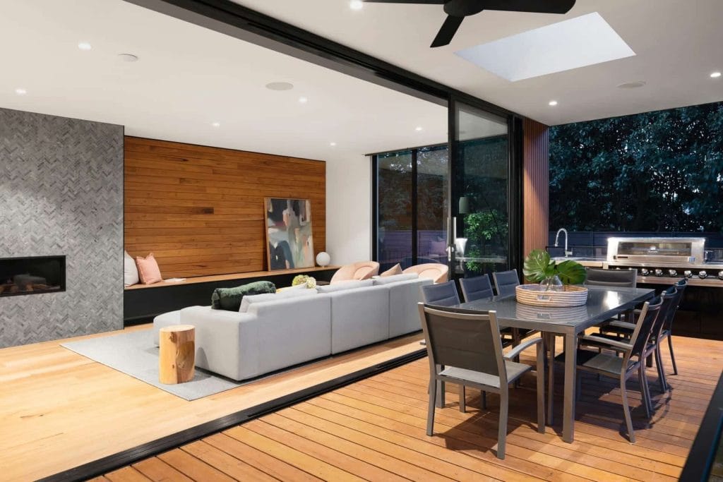 Panduan Lengkap: Cara Guna KWSP Akaun 2 Untuk Bina Rumah di Tanah Sendiri 7 Modern indoor-outdoor living space with a cozy sofa, dining table, and patio, featuring wood accents and a ceiling fan.