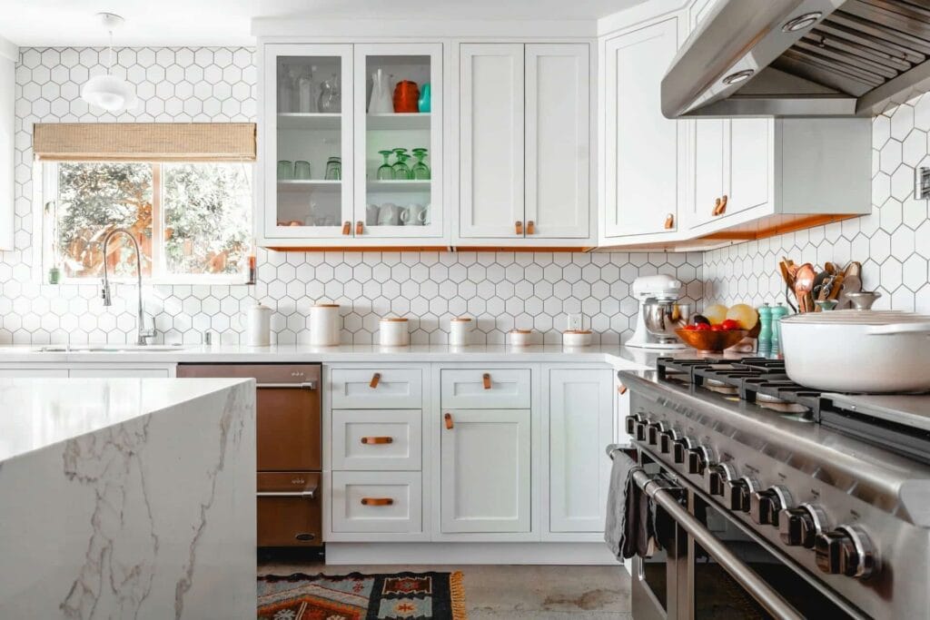 Panduan Lengkap: Cara Guna KWSP Akaun 2 Untuk Bina Rumah di Tanah Sendiri 1 Modern kitchen with white cabinets, stainless steel appliances, and hexagonal tile backsplash. Bright and stylish design.
