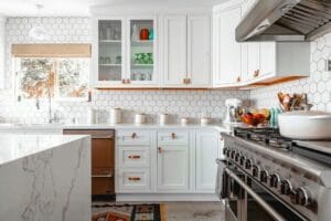 Modern kitchen with white cabinets, hexagonal tile backsplash, and stainless steel appliances.